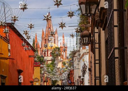 Stelle messicane di latta si stagliavano lungo la Calle Aldama acciottolata con il campanile rosa della Parroquia de San Miguel Arcangel che svetta sopra nel centro storico della città di San Miguel de Allende, Messico. Foto Stock