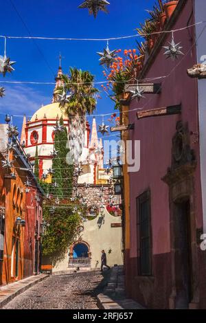 Stelle messicane di latta si stagliavano lungo la Calle Aldama acciottolata con il campanile rosa della Parroquia de San Miguel Arcangel che svetta sopra nel centro storico della città di San Miguel de Allende, Messico. Foto Stock