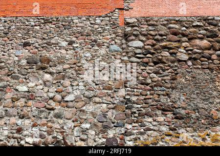 mura combinate di un antico castello, parte delle mura di un castello medievale fatto di pietre, ciottoli e mattoni rossi Foto Stock