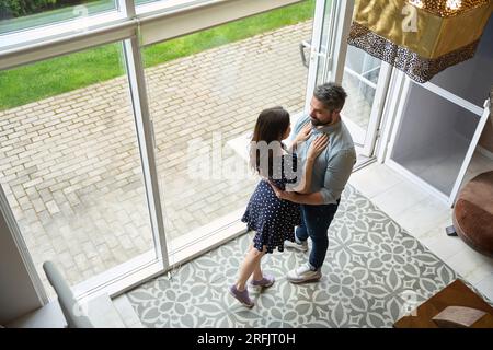 Marito e moglie felici stanno in piedi abbracciando in un soggiorno spazioso Foto Stock