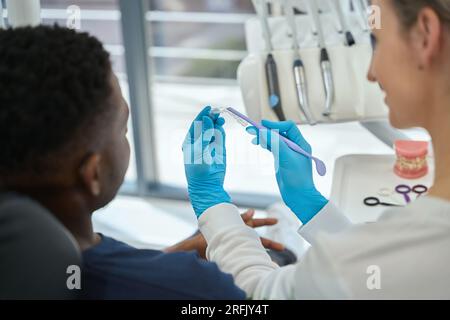 Dentista donna che mostra quale dente sarà raddrizzato indossando allineatori Foto Stock