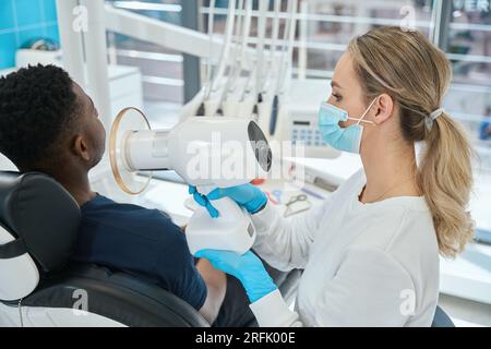 Stomatologa donna altamente qualificata che tiene radiografie portatili Foto Stock