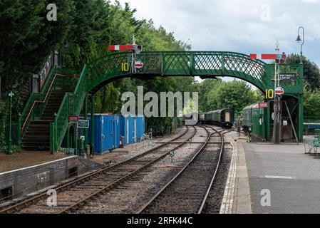 Piattaforma vuota e ponte alla stazione ferroviaria di Alresford con carrozze in lontananza. Parte della linea Watercress nell'Hampshire, in Inghilterra. Agosto 2023 Foto Stock