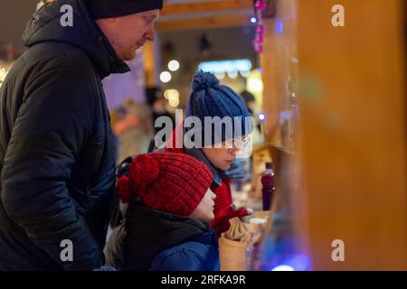 vacanze invernali in famiglia acquistando delle delizie al mercatino di natale. shopping invernale con bambini. Foto di alta qualità Foto Stock