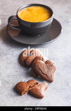 Biscotti a forma di cuore e tazza di caffè sul tavolo della cucina. Foto Stock