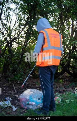 I sacchetti di plastica pieni di rifiuti vengono rimossi dai terreni di un centro sportivo dal team Community Payback. Foto Stock