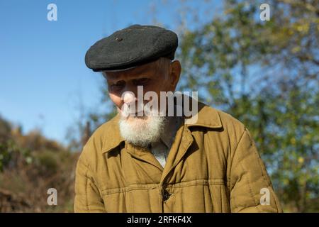 Vecchio con barba grigia e berretto. Uomo di 92 anni. Vecchio in giardino. Foto Stock