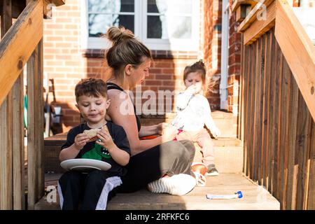 Mamma e bambini mangiano uno spuntino all'aperto nelle giornate di sole Foto Stock