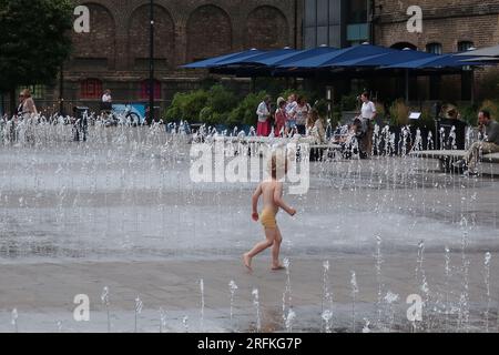 I bambini piccoli si divertono a correre attraverso le fontane danzanti e i getti d'acqua di Granary Square, il cuore della rinata King's Cross, Londra. Foto Stock