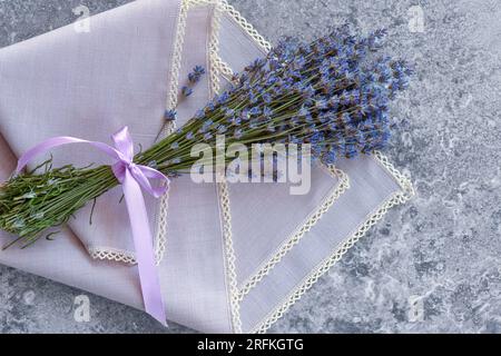 Un bouquet di lavanda su un tavolo in pietra grigia con un tovagliolo. Vista dall'alto. Spianatura piatta Foto Stock