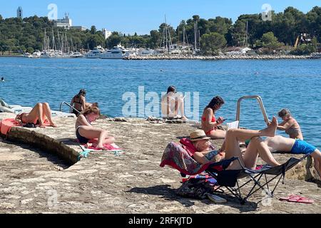 Porec, Kroatien. 30 luglio 2023. Plava Laguna, costa adriatica vicino a Porec/Croazia, spiaggia. I vacanzieri si trovano sulla spiaggia di pietra, sulla spiaggia rocciosa al sole e si rilassano e si rilassano. ? Credito: dpa/Alamy Live News Foto Stock