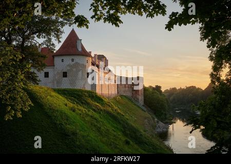 Vista dell'attrazione turistica lettone - le rovine del castello medievale di Bauska e i resti di un palazzo successivo al tramonto. Bauska, Lettonia. Foto Stock