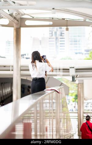 Una giovane ragazza thailandese si prende un momento nella stazione dello skytrain BTS di Chong Nonsi a Bangkok in Thailandia. Foto Stock