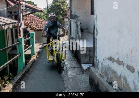 Un corriere di biciclette consegna i pacchi di merci all'indirizzo del cliente a Bogor, Giava Occidentale, Indonesia, il 1° agosto 2023 Foto Stock