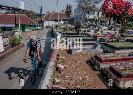 Bogor, Indonesia - 1 agosto 2023: I ciclisti camminano attraverso un cimitero a Bogor, Giava Occidentale. Foto Stock