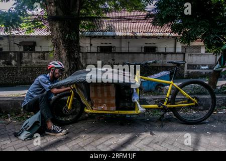 Bogor, Indonesia - 1 agosto 2023: Un corriere di biciclette trasporta un pacco di merci su una bicicletta cargo da consegnare all'indirizzo del cliente a Bogor Foto Stock