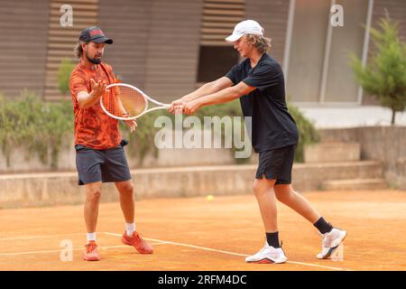 Padre insegna a suo figlio a giocare a tennis sul campo. Scatto medio Foto Stock