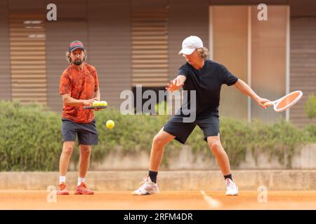 Padre insegna al figlio adolescente a giocare a tennis sul campo. Scatto medio Foto Stock