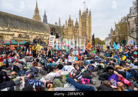 LONDRA - 22 aprile 2023: Confrontati con la scena di grande impatto dei manifestanti XR che partecipano a un massacro di massa, ponendo i loro corpi davanti al Parlamento a emp Foto Stock