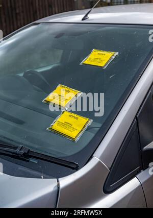Biglietti multipli per il parcheggio o avvisi di penalità sul parabrezza di un'auto parcheggiata in strada Foto Stock