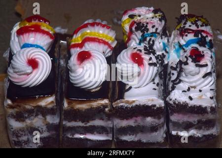 Varie fette di torte, torta arcobaleno, torta ai lamponi e torta alle mandorle. Dolci decorati con per le vacanze, attenzione selettiva Foto Stock