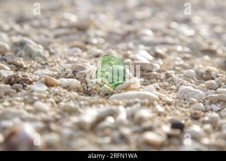 Splendido pezzo di vetro verde marino tra ciottoli sulla spiaggia. Primo piano. Foto Stock
