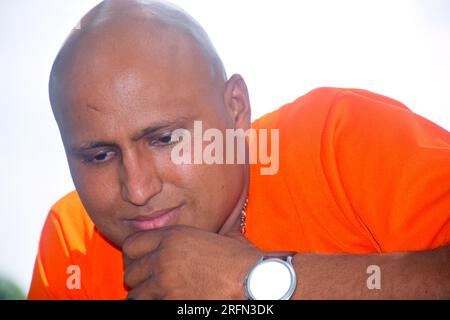 Graziosa modella calva che indossa una t-shirt arancione e un ritratto estivo sorridente e gioioso. Uomini allegri Foto Stock