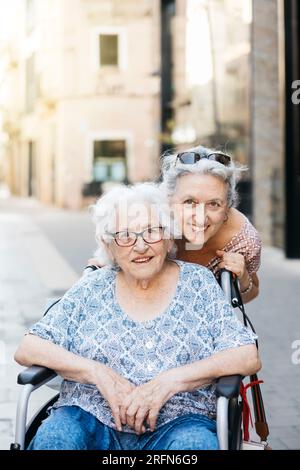 Ritratto di una donna anziana che si prende cura di sua madre su una sedia a rotelle. Donna che fa una passeggiata con sua madre che è su una sedia a rotelle. Foto Stock