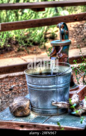 Un secchio metallico lucido appeso alla pompa dell'acqua dell'azienda agricola Foto Stock