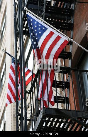 Due stelle e strisce americane sono appese sulle scale di fuga antincendio di New York. Foto Stock