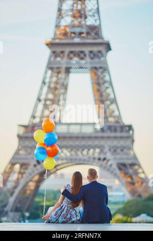Coppia amorevole con un mucchio di palloncini colorati che guardano la Torre Eiffel a Parigi, in Francia Foto Stock