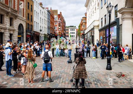 Un mago di strada ingoia una mongolfiera mentre si esibisce e intrattiene una folla entusiasta e apprezzata al Covent Garden nel West End di Londra, WC2 Foto Stock