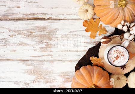 Accogliente doppio lato autunnale con zucche, foglie, maglione e latte con spezie alla zucca. Vista dall'alto verso il basso su uno sfondo rustico di legno bianco. Foto Stock