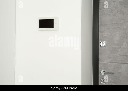 Videocitofono moderno su parete bianca vicino alla porta Foto Stock