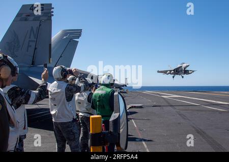 INDIAN OCEAN (4 agosto 2023) i marinai della Royal Australian Navy (RAN) assegnati alla fregata RAN HMAS Perth (FFG 157) osservano come F/A-18F Super Hornet, attaccati al Diamondbacks of Strike Fighter Squadron (VFA) 102, atterrano sul ponte di volo degli Stati Uniti L'unica portaerei della Marina dispiegata in avanti, la USS Ronald Reagan (CVN 76), durante un tour navale, nell'Oceano Indiano, il 4 agosto 2023. Ronald Reagan, l'ammiraglia del Carrier Strike Group 5, fornisce una forza pronta al combattimento che protegge e difende gli Stati Uniti, e sostiene alleanze, partnership e interessi marittimi collettivi nell'Indo-Pa Foto Stock