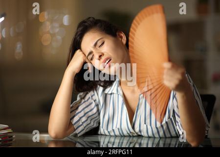 Donna sopraffatta che soffre di colpo di calore che si diffonde a casa di notte Foto Stock