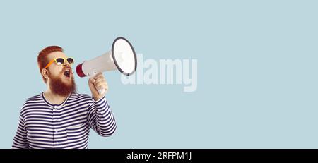 Un simpatico uomo caucasico che urla in stand di megafono in studio vicino allo spazio di copia Foto Stock