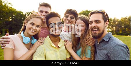 Ritratto di allegri e bellissimi amici multirazziali durante la loro divertente passeggiata nel parco estivo. Foto Stock