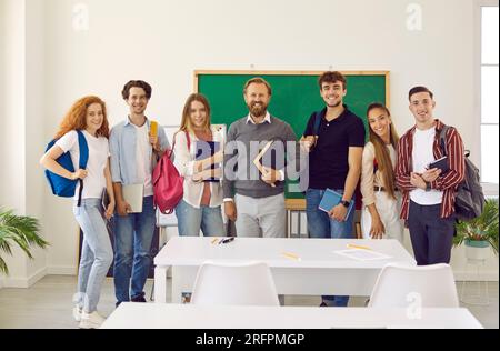 Ritratto di gruppo di studenti universitari sorridenti e felici insieme al loro insegnante preferito. Foto Stock