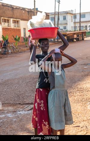 Due ragazze che si portano in testa in una strada a Jinja, in Uganda Foto Stock