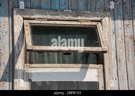 La finestra della vecchia casa in legno di legno sullo sfondo di pareti in legno. Foto Stock