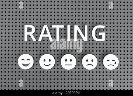 Concetto di valutazione del cliente. Testo ed emoticon su tavola grigia Foto Stock