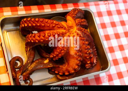 Polpo cotto in mostra sul tavolo del ristorante con tovaglie a quadri rosse e bianche, Vigo, Galizia, Spagna Foto Stock