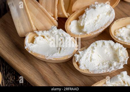 Cestino di cialde con crema cagliata all'interno, preparazione del dessert con crema bianca Foto Stock