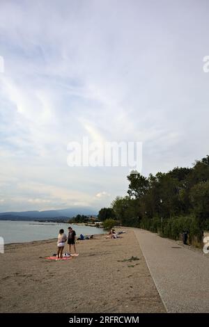 Passeggiata panoramica accanto a una riva del lago delimitata da un parco su un tramonto nuvoloso Foto Stock