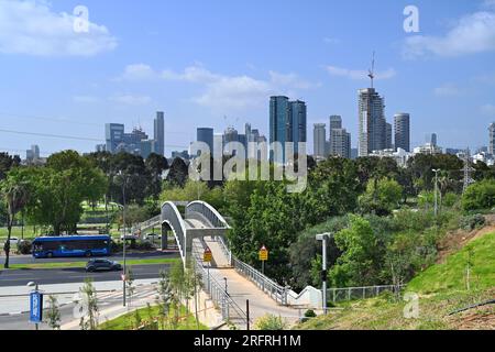 TEL AVIV-YAFO, ISRAELE - MAGGIO 2023: Ponte pedonale attraverso Rokach blvd fino al parco Yarkon sullo sfondo gli alti edifici di Ramat Gan Foto Stock