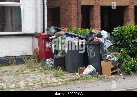 Slough, Berkshire, Regno Unito. 3 agosto 2023. Bidoni e sacchetti neri fuori casa a Slough, Berkshire. Slough Borough Council (SBC) ha recentemente introdotto una modifica alle collezioni di cestini dei residenti al fine di incoraggiare i residenti a riciclare di più. I contenitori grigi con rifiuti generici, compreso il cibo, vengono ora raccolti una volta ogni due settimane piuttosto che una volta alla settimana, con il riciclaggio in contenitori rossi, che vengono raccolti nella settimana alternata. Alcuni residenti di Slough stanno ora segnalando problemi con i vermi e gli odori di rifiuti non raccolti lasciati sulle strade, che probabilmente peggioreranno solo una volta che le temperature Foto Stock