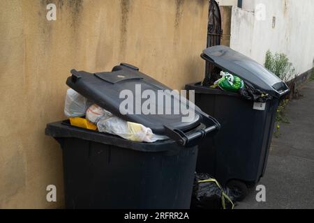 Slough, Berkshire, Regno Unito. 3 agosto 2023. Bidoni e sacchetti neri fuori casa a Slough, Berkshire. Slough Borough Council (SBC) ha recentemente introdotto una modifica alle collezioni di cestini dei residenti al fine di incoraggiare i residenti a riciclare di più. I contenitori grigi con rifiuti generici, compreso il cibo, vengono ora raccolti una volta ogni due settimane piuttosto che una volta alla settimana, con il riciclaggio in contenitori rossi, che vengono raccolti nella settimana alternata. Alcuni residenti di Slough stanno ora segnalando problemi con i vermi e gli odori di rifiuti non raccolti lasciati sulle strade, che probabilmente peggioreranno solo una volta che le temperature Foto Stock