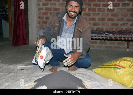09-12-2021 Indore, Madhya Pradesh, India. Agricoltore indiano che mescola diversi elementi fertilizzanti nel letame, a casa. messa a fuoco selettiva Foto Stock