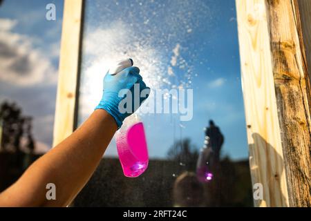 Vista ritagliata dell'attrezzatura per le mani delle donne per lavare e pulire la finestra dall'esterno Foto Stock